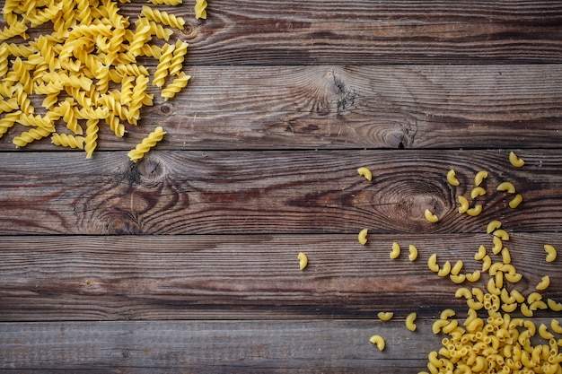 Mixed dried pasta selection on wooden background. Flat lay top view with copyspace for text, logo or other.