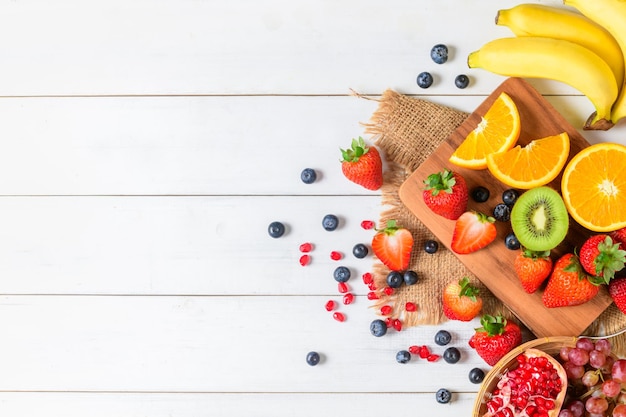 Foto insalata mista di frutta fresca con fragole mirtillo arancione su fondo bianco di legno dieta