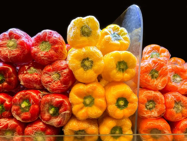 Mixed fresh peppers Wrapped in Cellophane Film Red Peppers Yellow Peppers Orange Peppers Tops close up whole