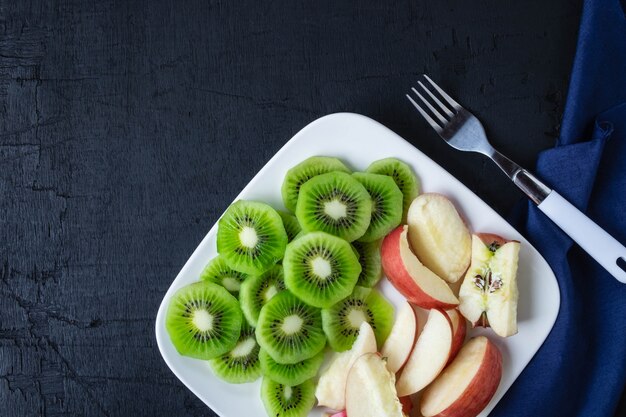 Mixed Fruit  fresh kiwi and apples with grapes in a plate on a wooden table.