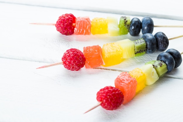 Mixed fruits and berries on white wooden table. 