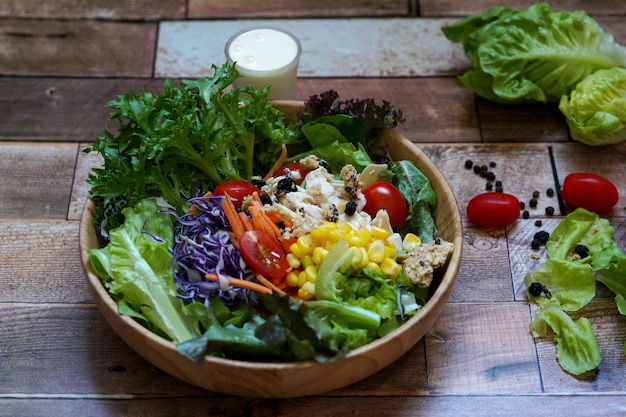 Mixed greens salad boiled chicken in a wooden bowl