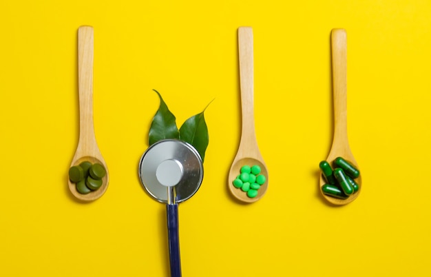 Mixed herbal tablets on a wooden spoon. Food supplement. Selective focus