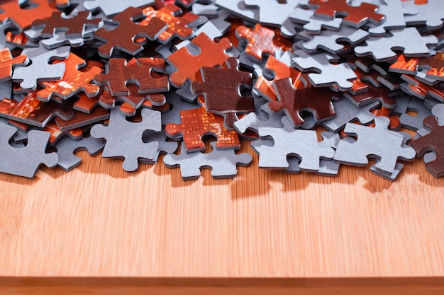 Mixed jigsaw puzzle peaces on wooden table