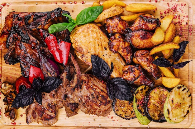 Photo mixed meat dish grilled ribs chicken wings rack of lamb with vegetables