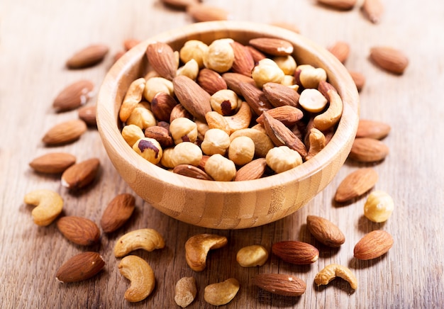 Mixed nuts in a bowl on wooden table
