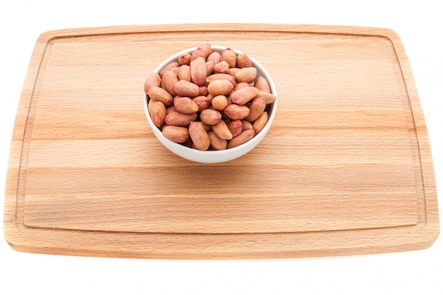 Mixed nuts in a metal brown bowl on a white wooden cutting board