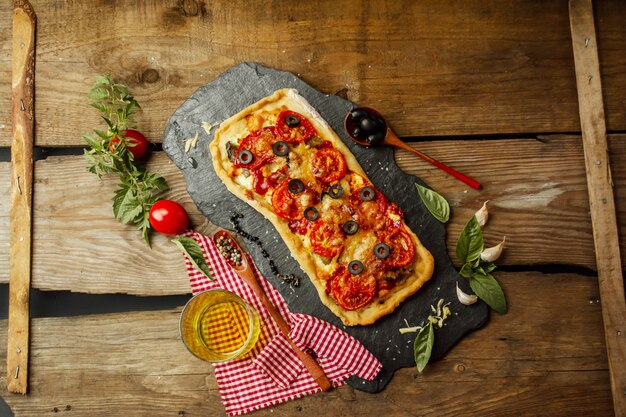 Mixed pizza with chicken, pepper, olives, onion, basil on pizza board