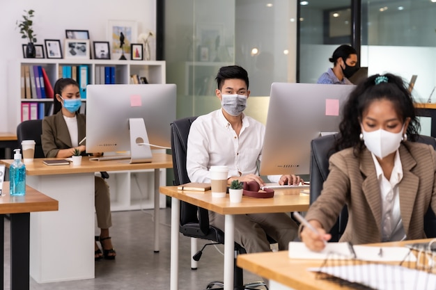 Mixed race of African black and asian business woman wear face mask working in new normal office.