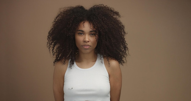 Mixed race black woman portrait with big afro hair curly hair in beige background