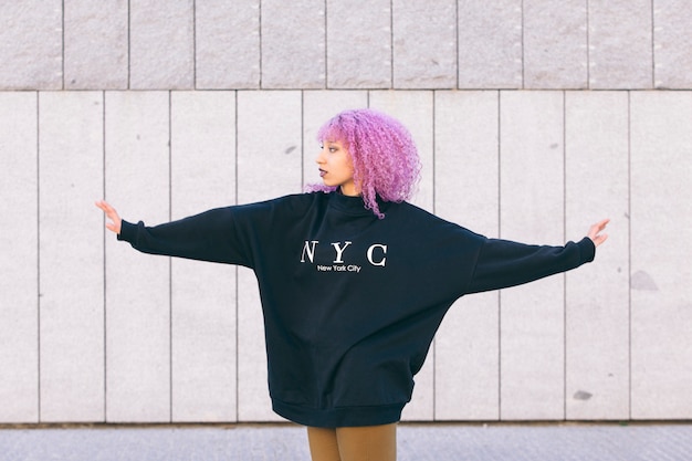 Mixed race black woman with purple afro hair and a New York sweater