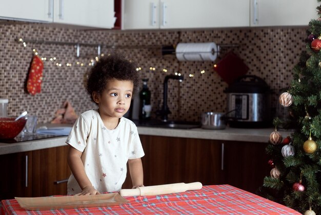 自宅でクリスマスの子供のために飾られたキッチンで肌の色が濃い混血の少年