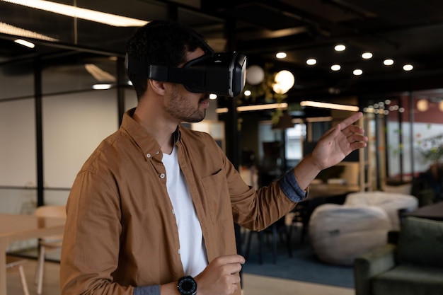 mixed race businessman wearing virtual reality headset in creative office. technology and social distancing in business office workplace during covid 19 coronavirus pandemic.