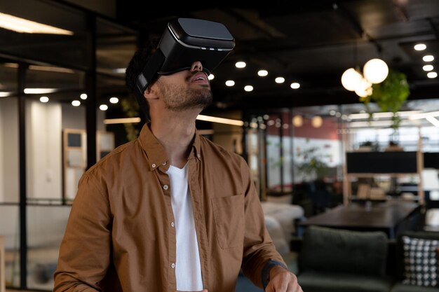 mixed race businessman wearing virtual reality headset in creative office. technology and social distancing in business office workplace during covid 19 coronavirus