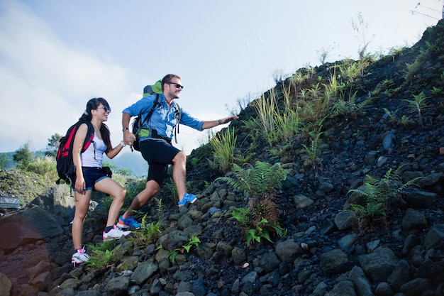 Mixed race couple go trekking together, walking on an uphill