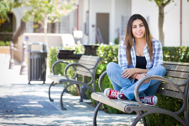 Photo mixed race female student portrait on school campus bench