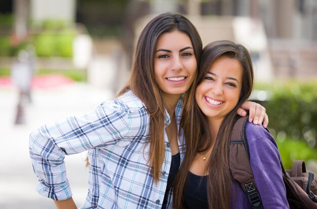 Foto studenti femminili di razza mista che portano zaini nel campus scolastico