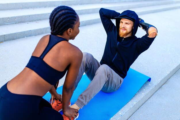 Mixed race friends fitness training together outdoors summer morning