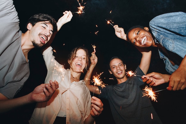 Photo mixed race friends playing with sparklers celebration and festive party concept