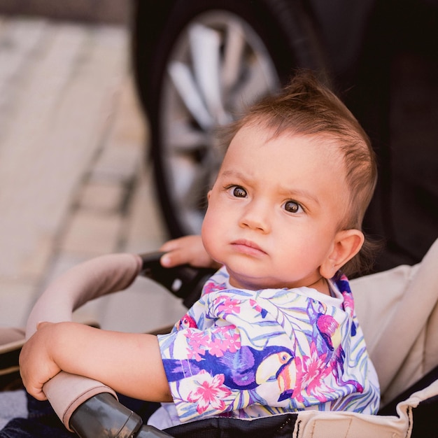 mixed race little boy sitting in the baby carriage in warm day outdoor Childhood concept