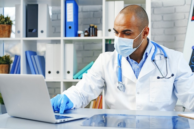 Mixed race male doctor sitting at his working table in hospital