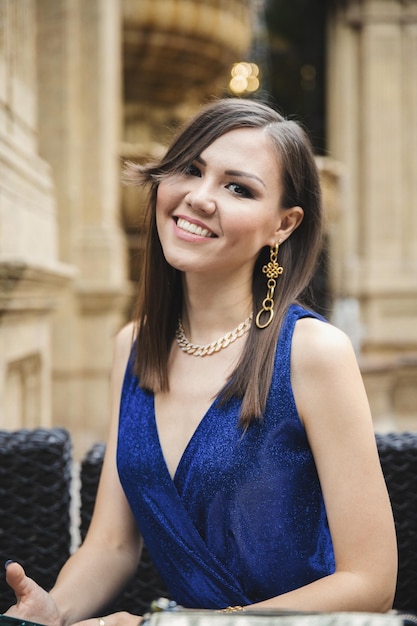 Mixed race pretty smiling woman in blue dress in street cafe portrait