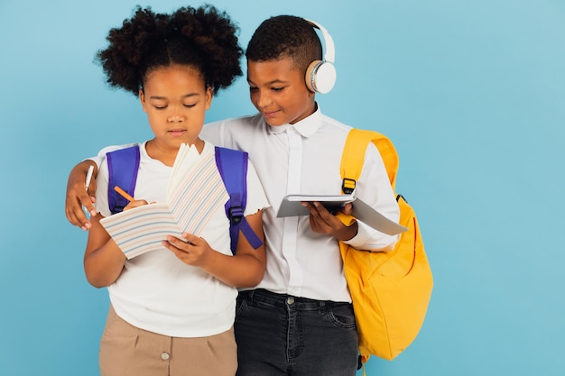 A mixed race schoolboy and an African American schoolgirl are reading an outline together in a school classroom on a blue background back to school concept