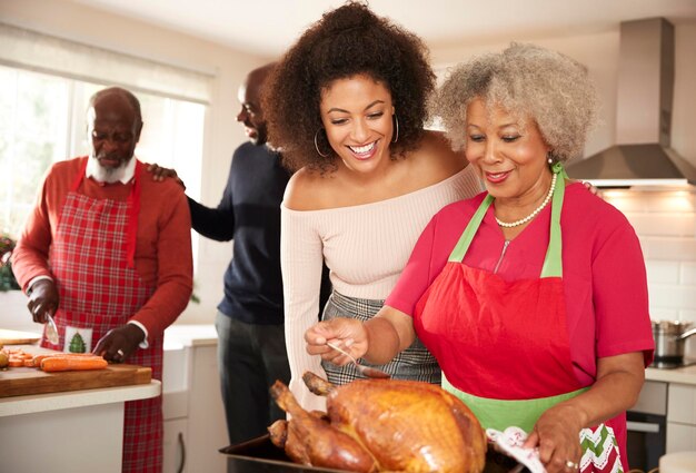 Mixed race senior and young adult family members talking in the kitchen while preparing Christmas dinner together close up