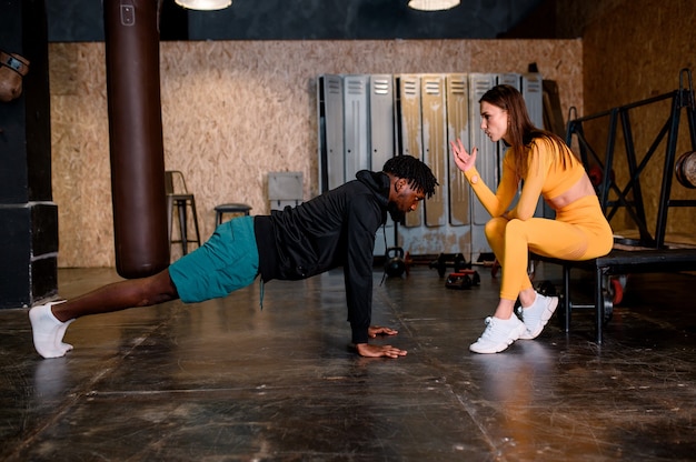 Mixed race sporty man with his girl doing exercise. Multi ethnic couple. High quality photo