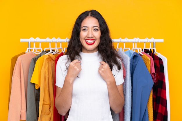 Mixed race woman in a clothing store celebrating a victory