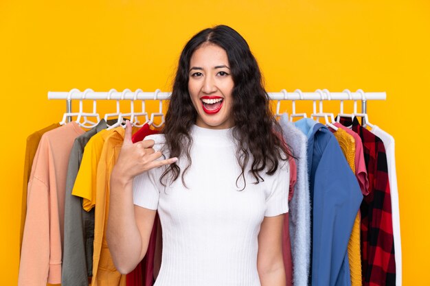 Mixed race woman in a clothing store making phone gesture