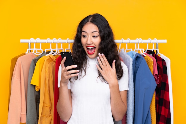 Mixed race woman in a clothing store and talking to mobile