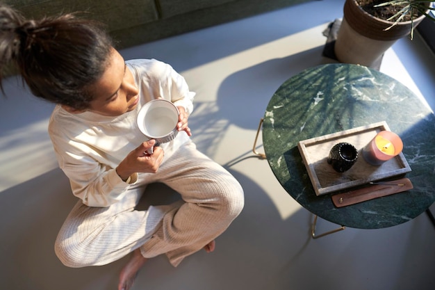 Photo mixed race woman sitting at the floor and enjoying at home