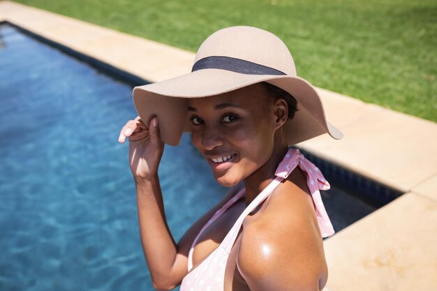 Mixed race woman spending time at home, relaxing and sunbathing by the pool. self isolating and social distancing in quarantine lockdown during coronavirus covid 19 epidemic