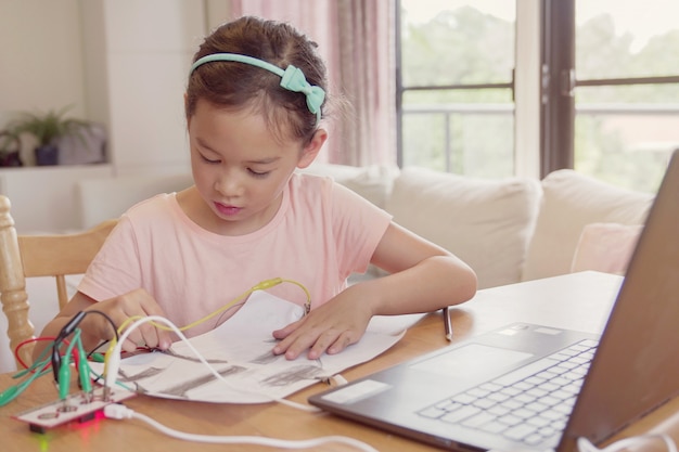 Razza mista giovane ragazza asiatica che impara a programmare insieme, bambino che impara da remoto a casa, scienza stem, educazione homeschooling, distanza sociale, concetto di isolamento