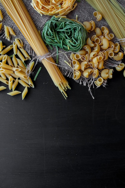 Mixed raw pasta on black background