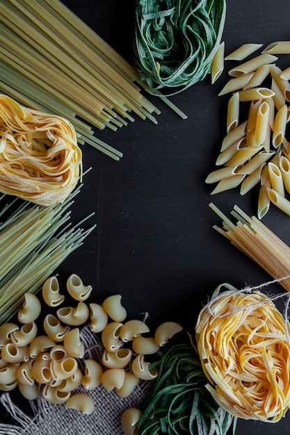 Mixed raw pasta on black background