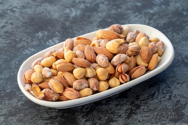 Mixed roasted nuts on plate on dark background