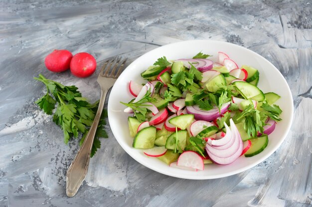 mixed salad with cucumber garden radish and onion and parsley with a fork