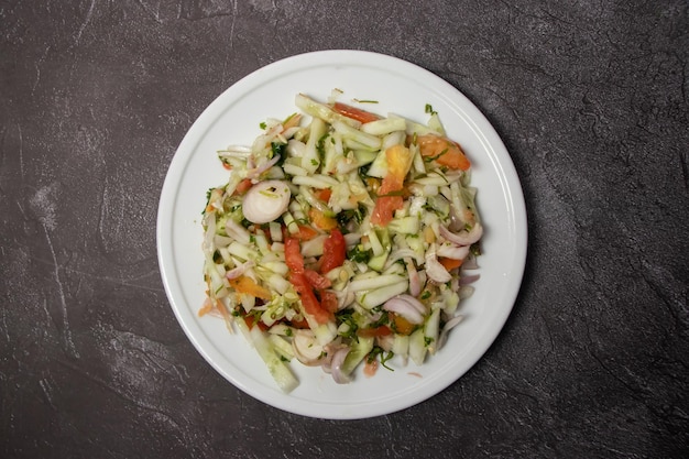 Смешанный салат с огурцом, луком и помидорами, подаваемый в блюде, изолированном на фоне.