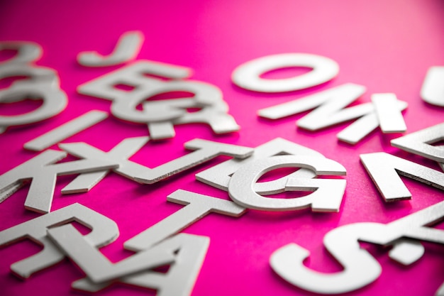 Photo mixed solid letters pile close up view photo. education concept on pink background.