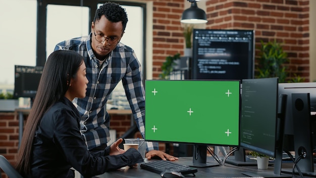 Mixed team of programmers analyzing source code looking at green screen chroma key mockup discussing algorithm. App developers working on online cloud computing in server room.