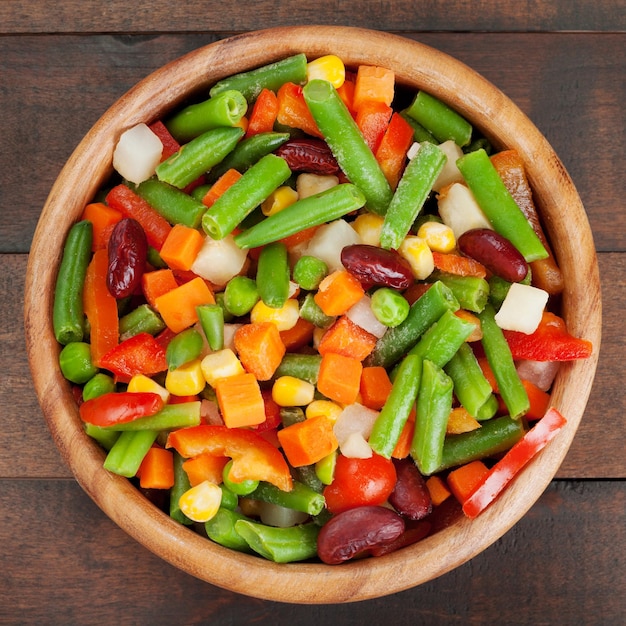 Mixed vegetables in wooden bowl on kitchen table top view