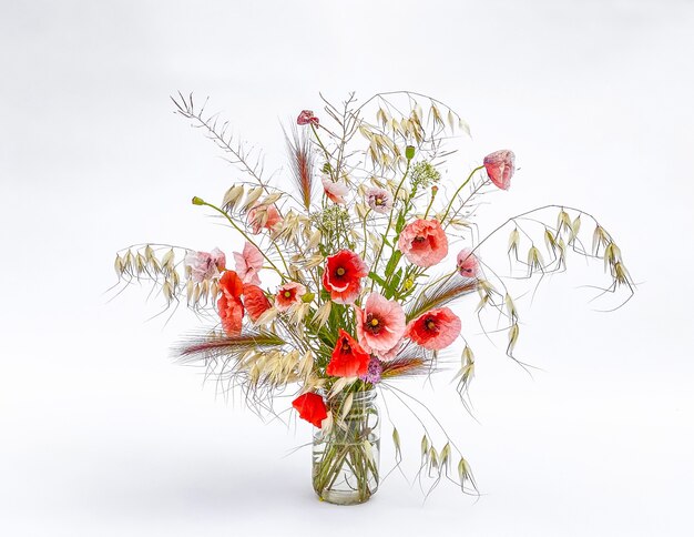 Mixed wild flowers bouquet and grasses in a glass vase. Poppy.