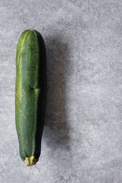 Mixed yellow, white, stripped and green zucchini's on a grey concrete background