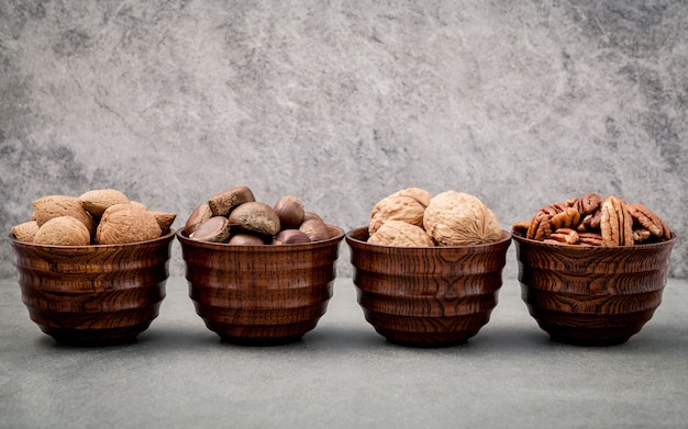 Mixex nuts in wooden bowl setup with stone background.  