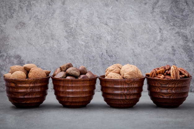 Mixex nuts in wooden bowl setup with stone background.