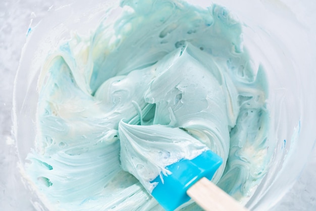 Mixing in blue food coloring into the buttercream frosting