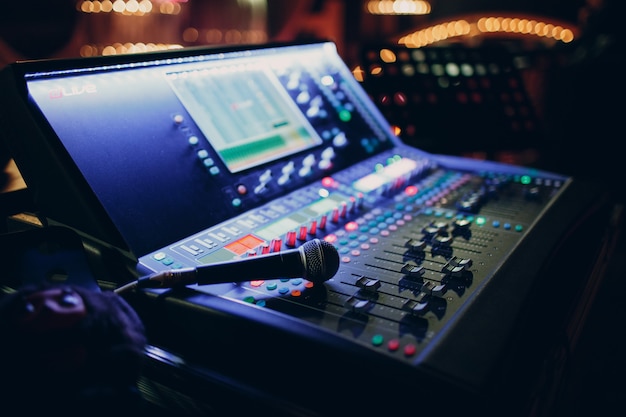 Photo mixing console and microphone, hand equalizing audio sound channels in night club