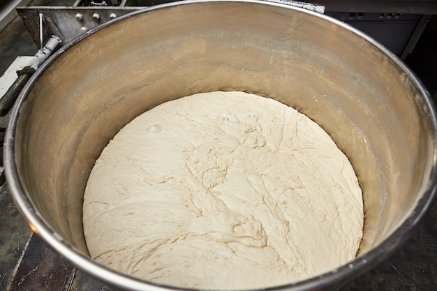 Mixing dough with professional kneader machine at the manufacturing. Equipment for making flour products